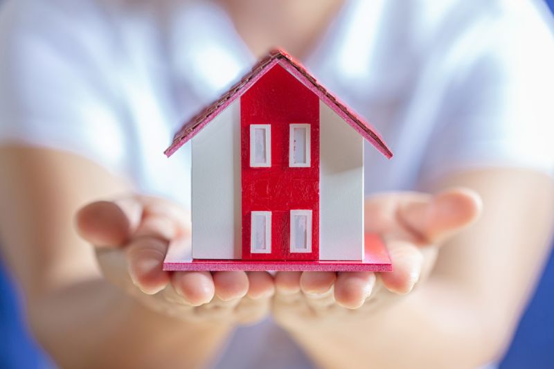Human hands holding model of dream house